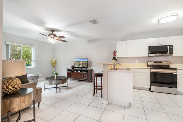 kitchen featuring sink, a breakfast bar area, white cabinets, kitchen peninsula, and stainless steel appliances