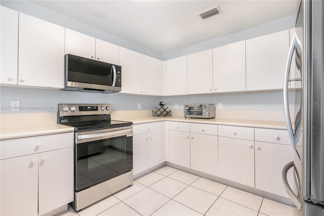 kitchen featuring stainless steel appliances, light tile patterned floors, and white cabinets