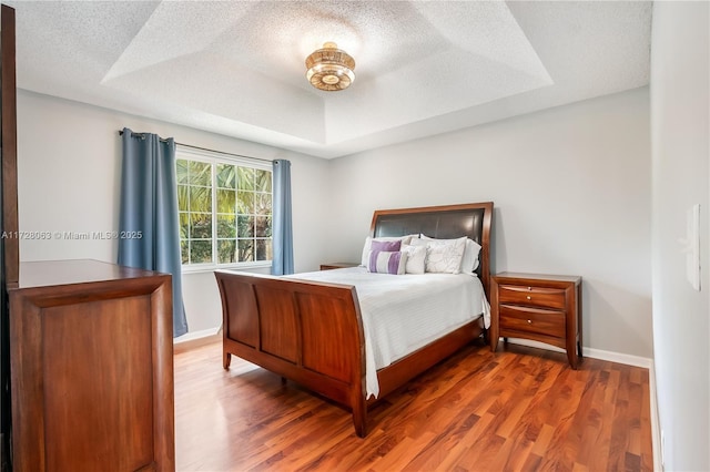 bedroom with a raised ceiling and hardwood / wood-style flooring