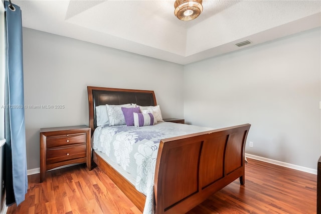 bedroom featuring hardwood / wood-style flooring and a raised ceiling