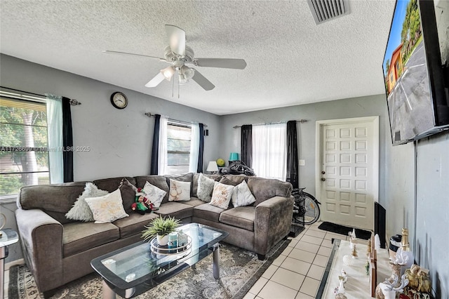 tiled living room featuring ceiling fan and a textured ceiling