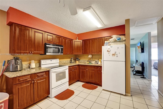 kitchen with light stone countertops, white appliances, light tile patterned floors, and a textured ceiling