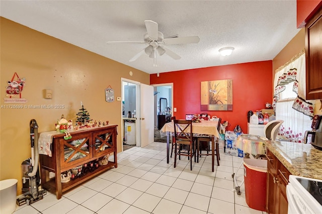 tiled dining area with a textured ceiling and ceiling fan