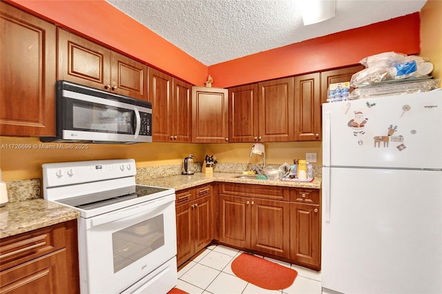 kitchen featuring light stone countertops, white appliances, light tile patterned floors, and a textured ceiling