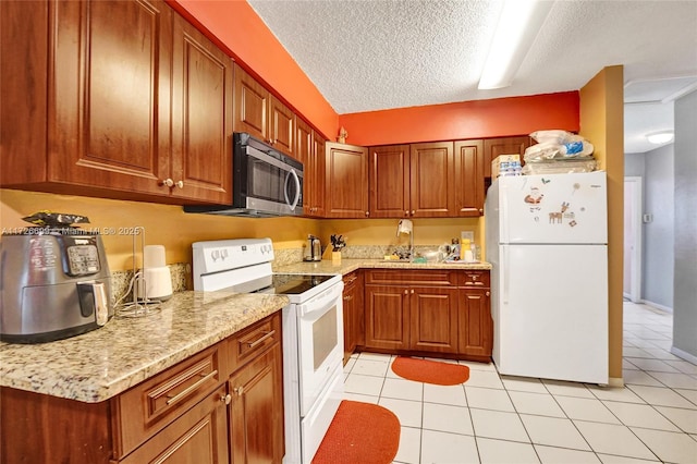 kitchen with sink, light stone countertops, light tile patterned flooring, white appliances, and a textured ceiling