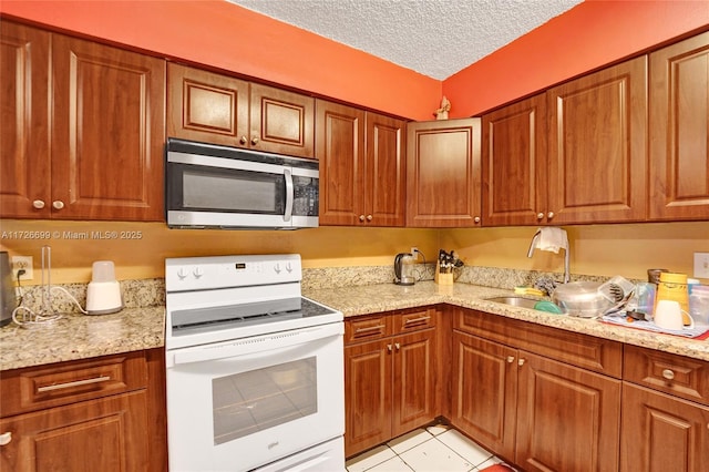 kitchen with light stone countertops, electric range, light tile patterned floors, and a textured ceiling