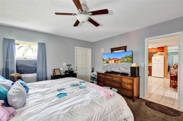 tiled bedroom with ceiling fan, white fridge, and a textured ceiling