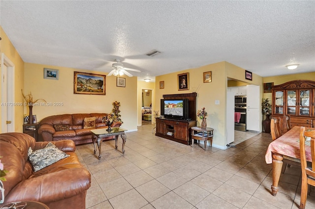 living room with ceiling fan, a textured ceiling, and light tile patterned floors