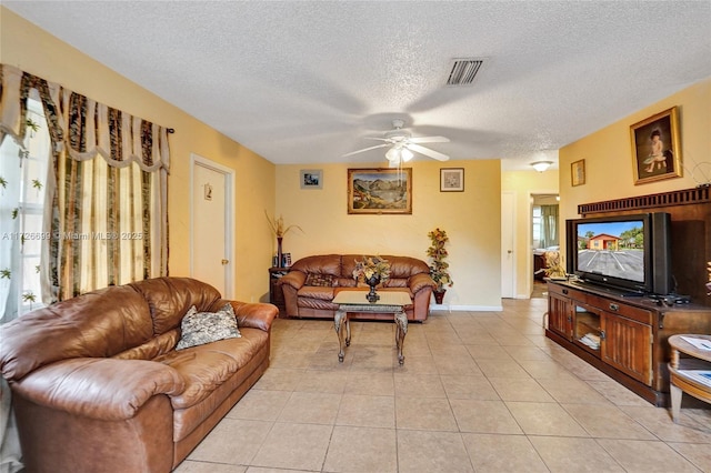 living room featuring a textured ceiling, light tile patterned floors, and ceiling fan