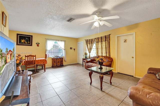 living room featuring light tile patterned flooring, a textured ceiling, and ceiling fan