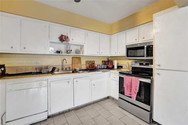 kitchen featuring sink, white cabinetry, light tile patterned floors, and stainless steel appliances