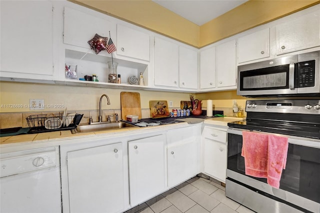 kitchen with white cabinets, light tile patterned floors, appliances with stainless steel finishes, and sink