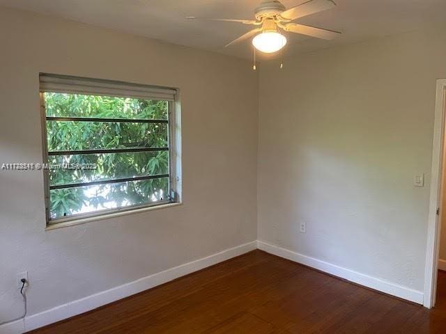 spare room with dark wood-type flooring and ceiling fan