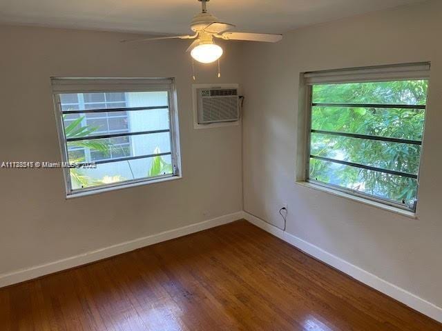 empty room with ceiling fan, an AC wall unit, and dark hardwood / wood-style flooring