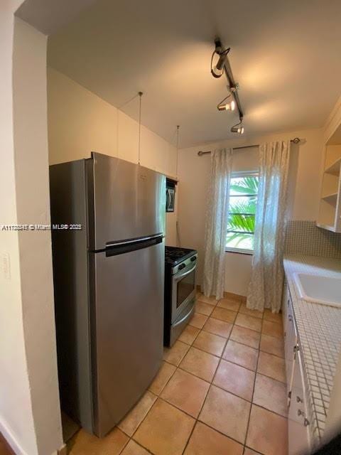 kitchen with appliances with stainless steel finishes, rail lighting, white cabinetry, and sink