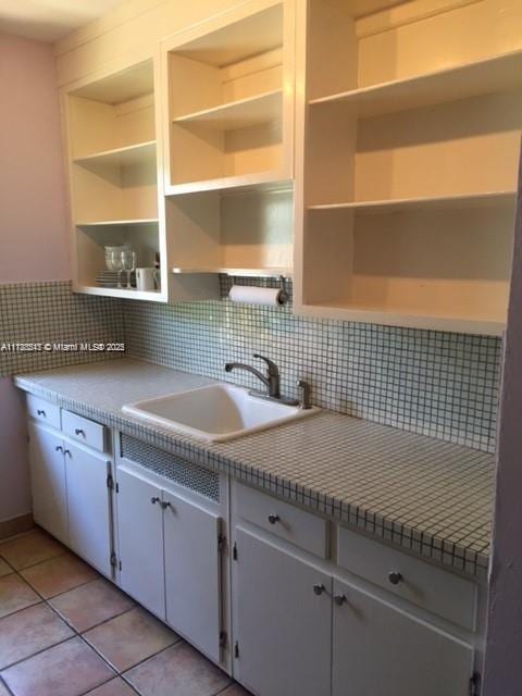 kitchen featuring white cabinets, sink, and light tile patterned flooring