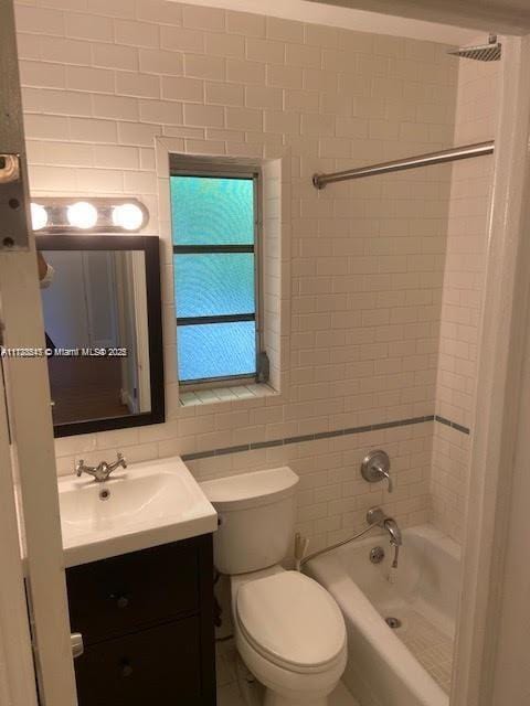 full bathroom with toilet, vanity, tile walls, and tiled shower / bath