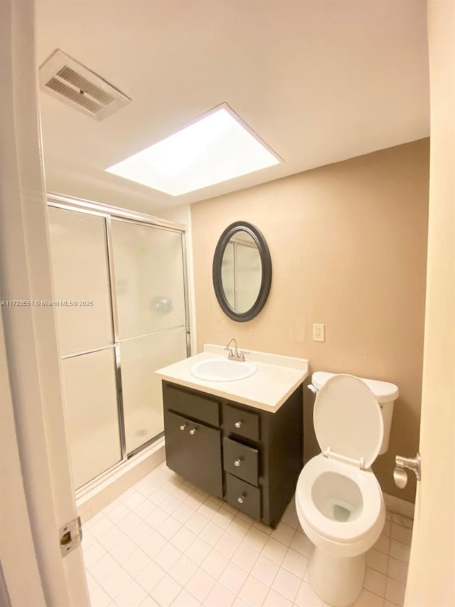 bathroom featuring walk in shower, toilet, a skylight, vanity, and tile patterned flooring