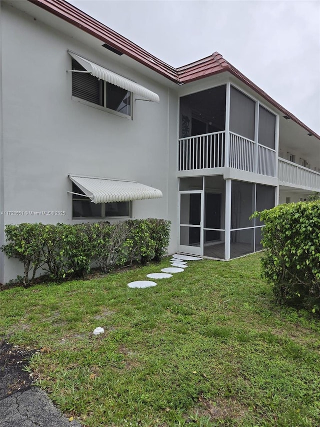 back of property featuring a yard and a sunroom