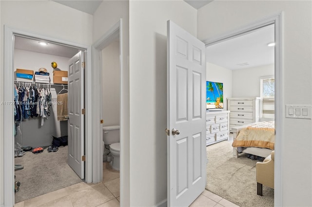 bathroom with tile patterned flooring, a spacious closet, and toilet