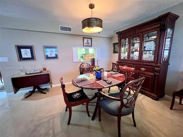 carpeted dining space featuring a textured ceiling