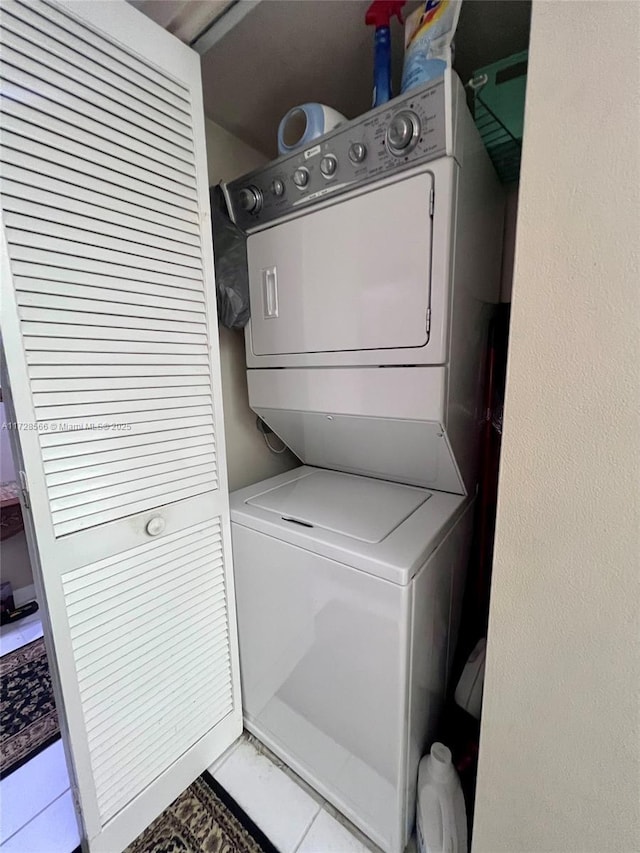 laundry room with stacked washer / dryer and light tile patterned flooring