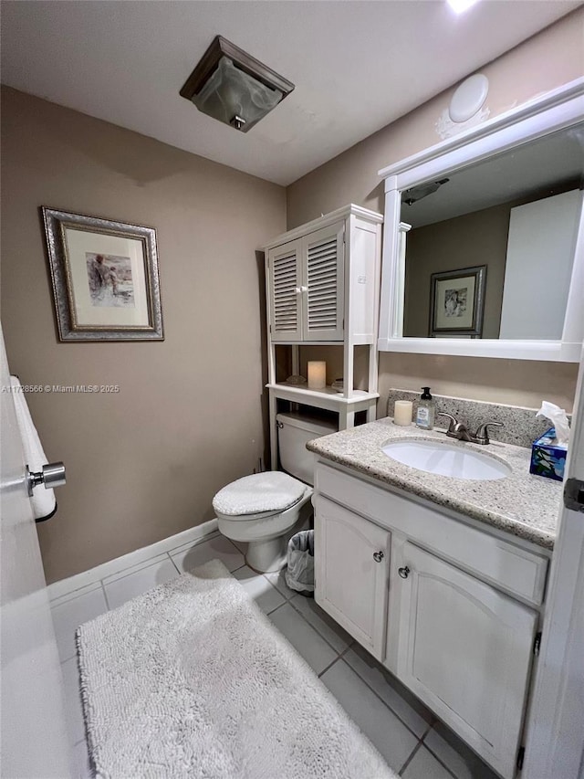 bathroom with toilet, vanity, and tile patterned flooring