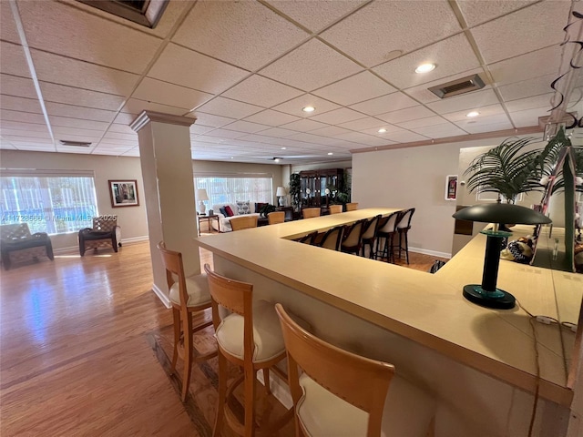 bar featuring a paneled ceiling, light hardwood / wood-style flooring, and a healthy amount of sunlight