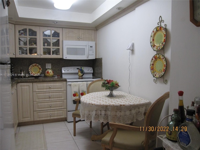 kitchen with backsplash, white appliances, light tile patterned floors, and a raised ceiling