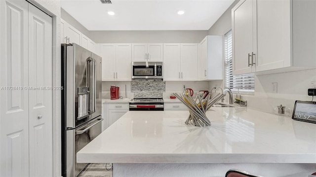 kitchen featuring white cabinetry, stainless steel appliances, and kitchen peninsula