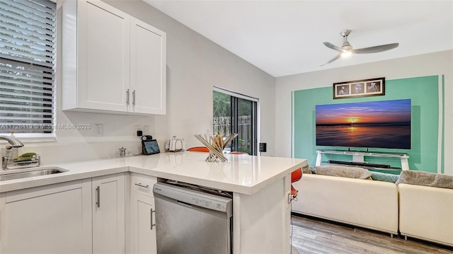 kitchen featuring white cabinets, dishwasher, sink, kitchen peninsula, and light hardwood / wood-style flooring