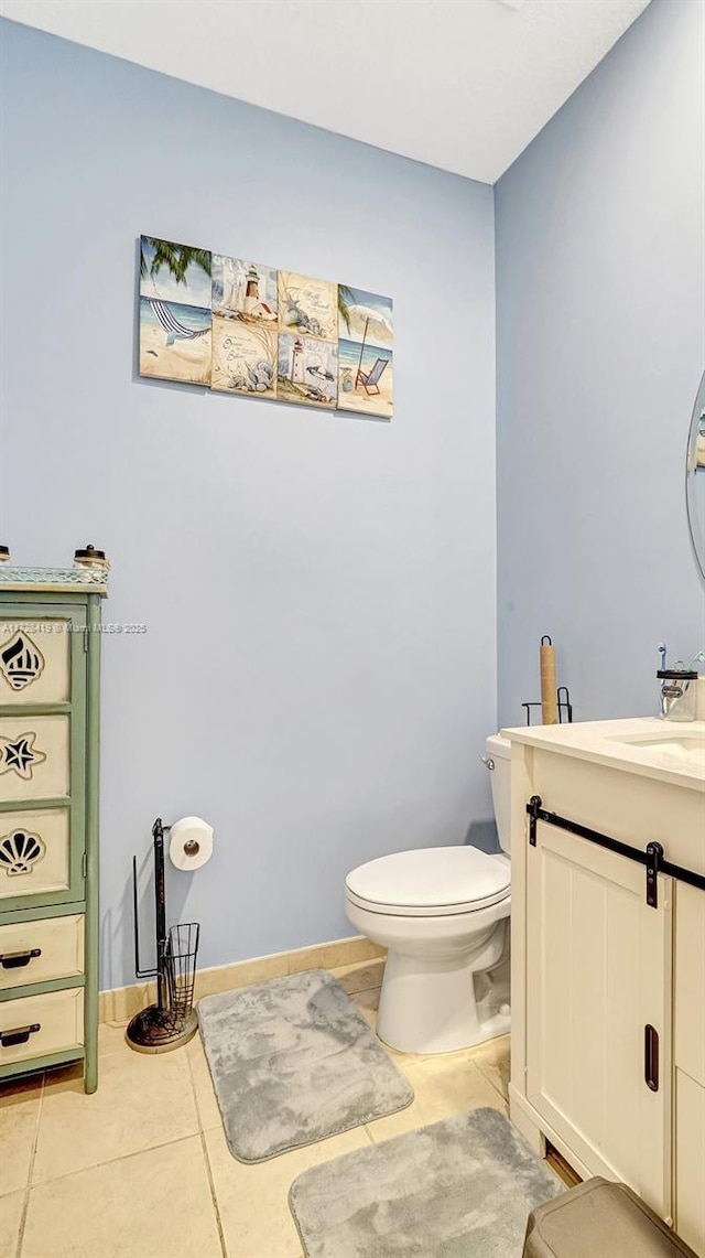 bathroom with toilet, vanity, and tile patterned flooring