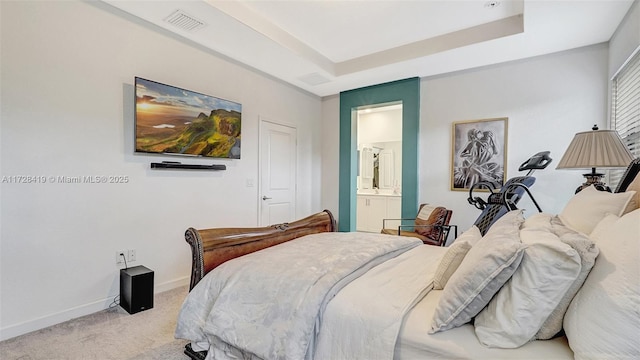 carpeted bedroom with connected bathroom and a raised ceiling