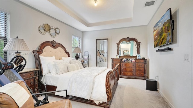 bedroom with light carpet and a raised ceiling