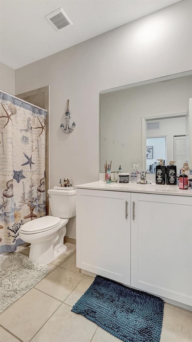 bathroom featuring toilet, vanity, a shower with curtain, and tile patterned floors