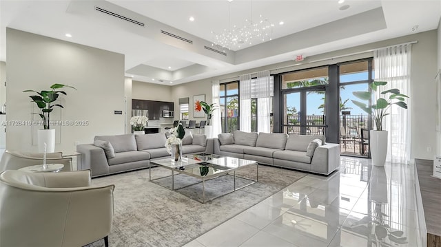 living room with light tile patterned floors, french doors, an inviting chandelier, and a tray ceiling