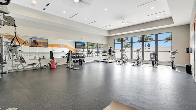 gym with ceiling fan and a tray ceiling