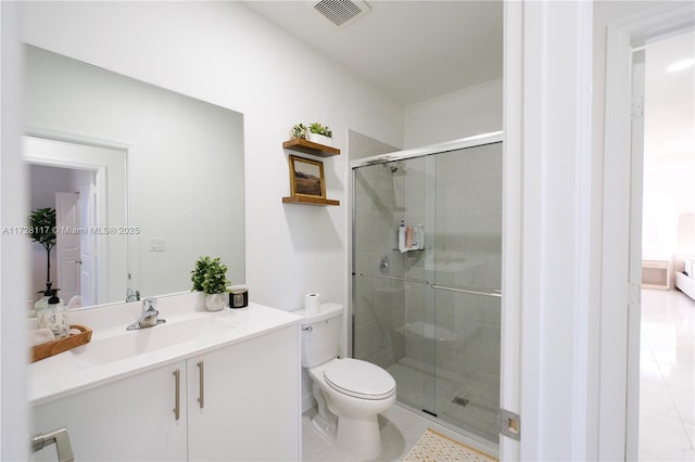 bathroom with a shower with door, vanity, tile patterned floors, and toilet