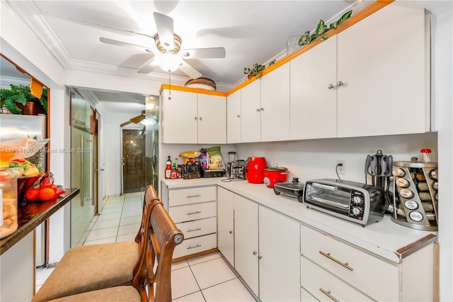 kitchen featuring ceiling fan, white cabinetry, light tile patterned floors, and crown molding