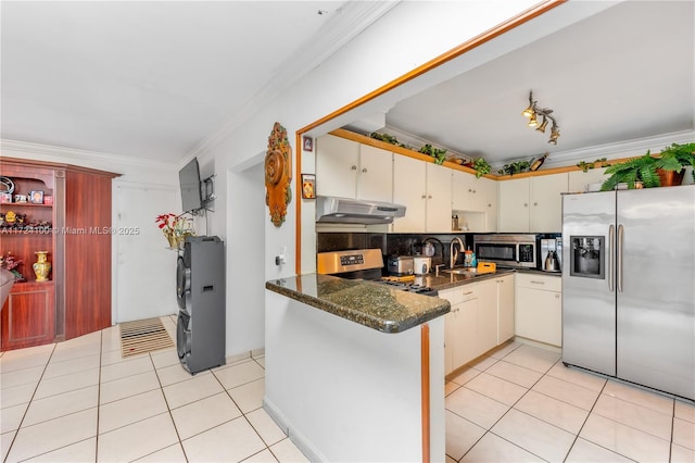 kitchen with light tile patterned floors, kitchen peninsula, stainless steel appliances, dark stone countertops, and crown molding