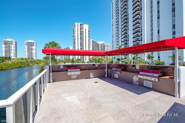 view of patio / terrace featuring a water view, exterior kitchen, and a grill