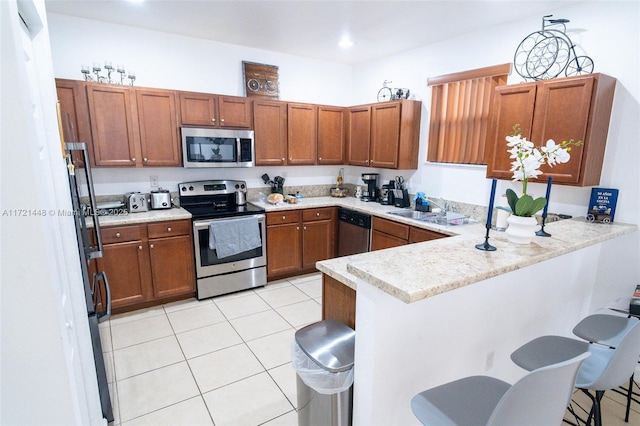 kitchen featuring sink, stainless steel appliances, kitchen peninsula, and a breakfast bar