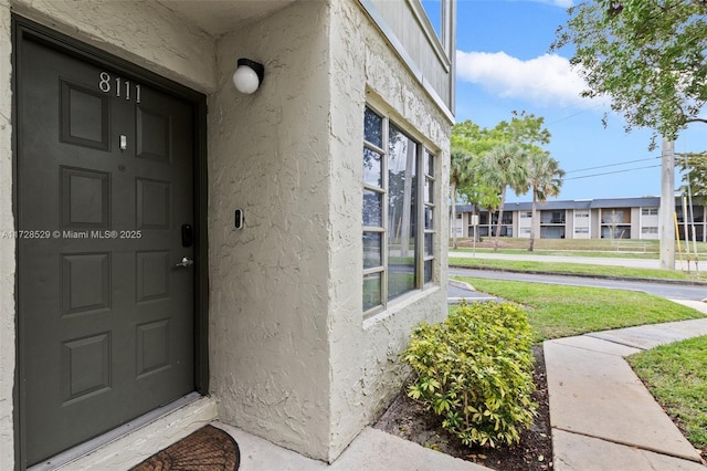 doorway to property featuring a lawn