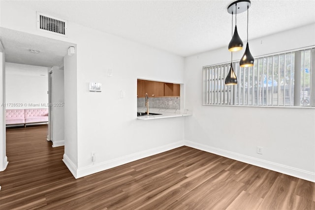 unfurnished room with dark hardwood / wood-style floors, sink, and a textured ceiling