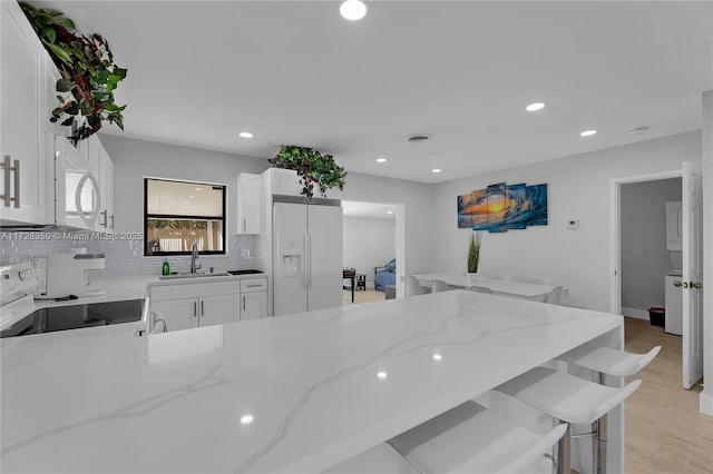 kitchen featuring light stone countertops, white appliances, and white cabinets