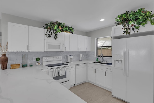 kitchen featuring backsplash, sink, white appliances, white cabinets, and light stone counters