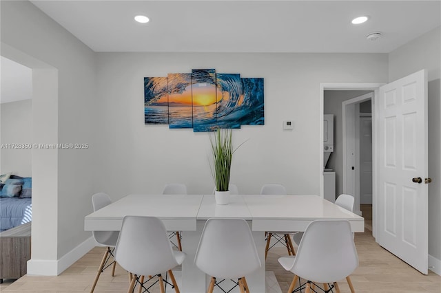 dining room featuring light wood-type flooring and stacked washer / dryer