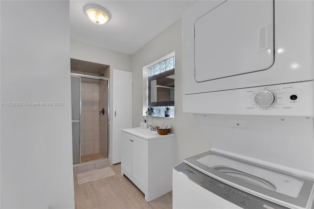 bathroom with walk in shower, stacked washer and dryer, and vanity