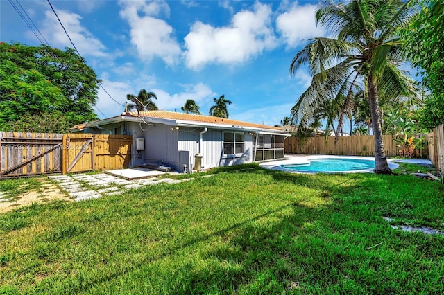 rear view of property with a fenced in pool and a lawn