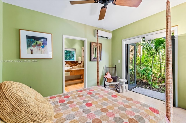 bedroom with ceiling fan, a wall mounted AC, access to exterior, ensuite bath, and light wood-type flooring